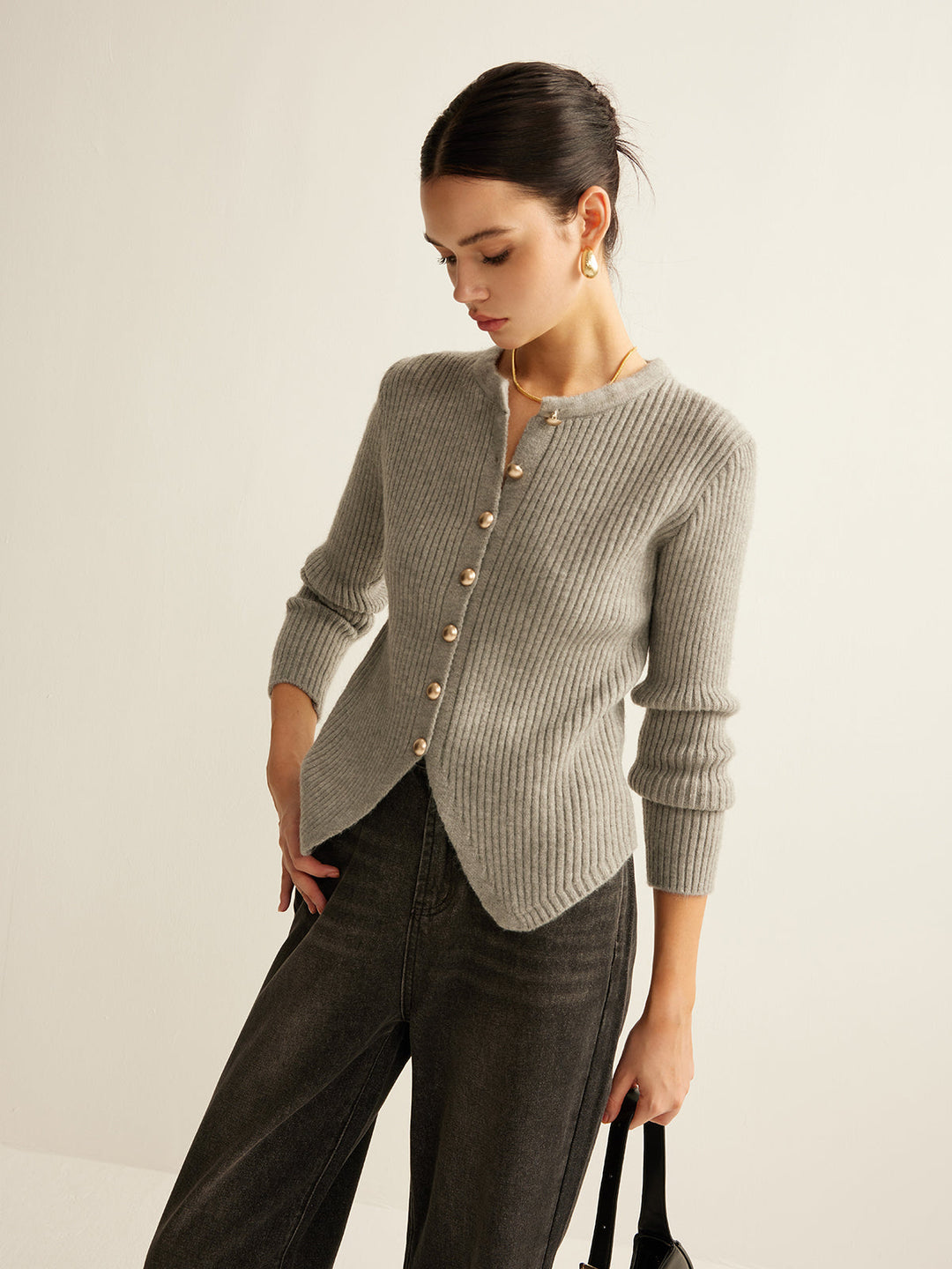 Frau trägt grauen Strickcardigan mit Knopfleiste, kombiniert mit schwarzer Hose.