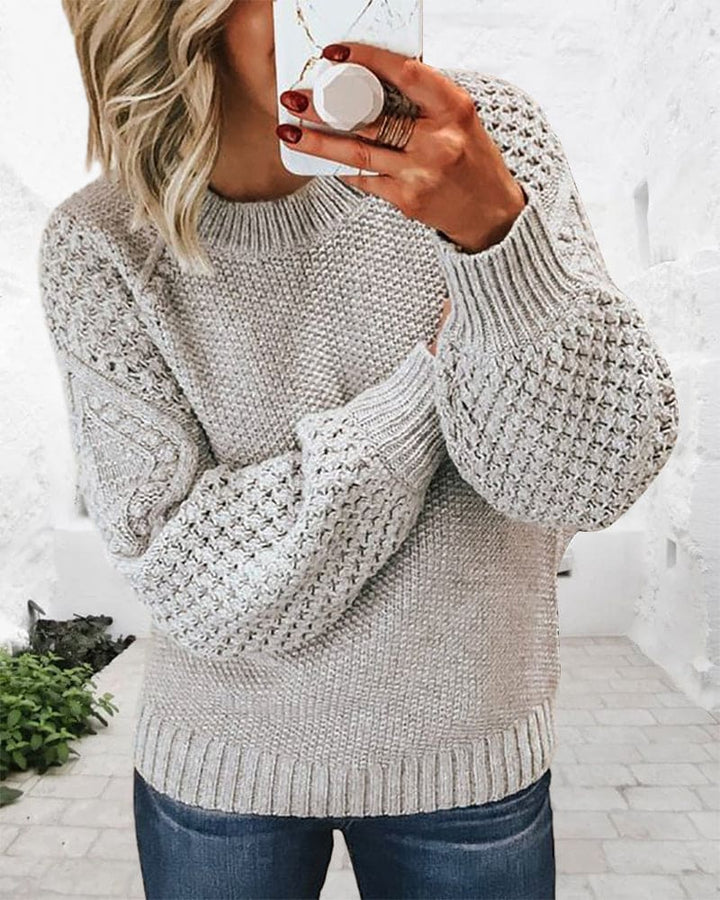 Frau in grauem Strickpullover mit Zopfmuster, lässig, modisch, Herbstmode, gemütlich.