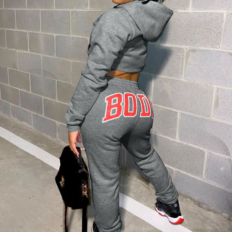 Graues Damen-Sportset mit Kapuzenpullover und Jogginghose, roter "BODY"-Aufdruck, Fitnessmode.