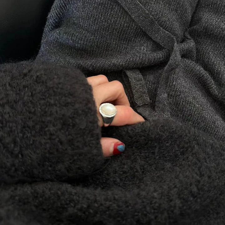Dunkelgrauer Wollpullover, Hand mit silbernem Ring, gemütliche Wintermode, Nahaufnahme.