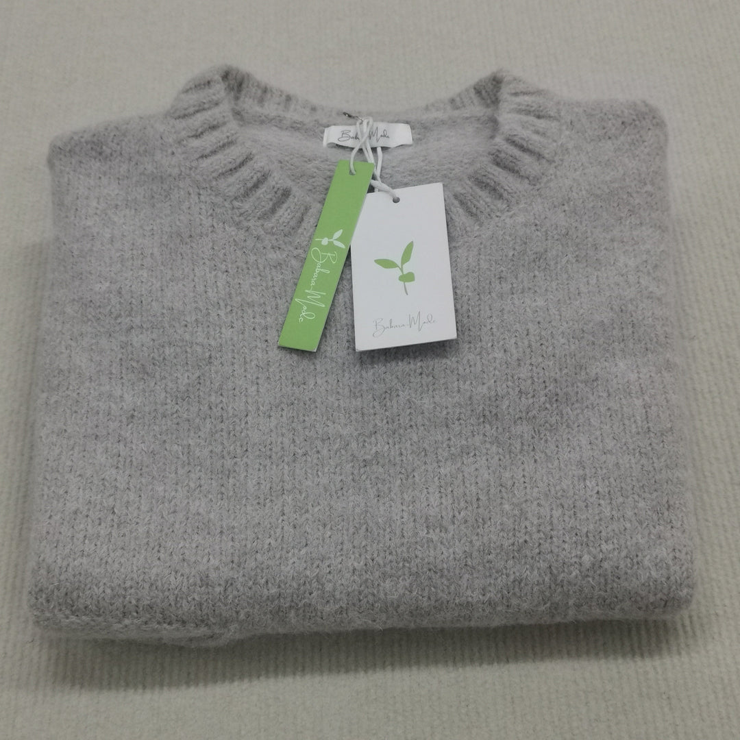 Grauer Kaschmirpullover, gefaltet, mit Etikett, weiches Material, nachhaltige Mode.