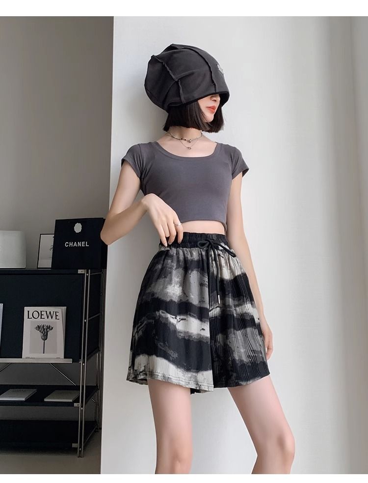 Frau in grauem Crop-Top und schwarz-weißem Rock, modisch, modern, stilvoll, Innenraum.