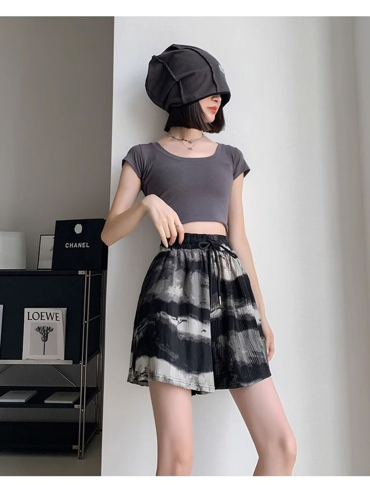 Frau in grauem Crop-Top und schwarz-weißem Rock, modisch, modern, stilvoll, Innenraum.