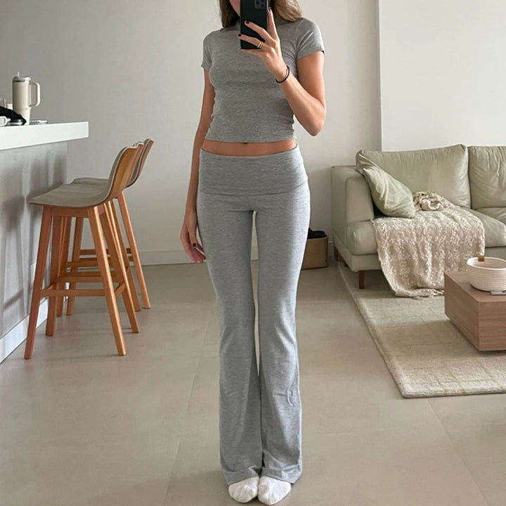 Frau in grauem Yoga-Set, Wohnzimmer, moderne Einrichtung, bequeme Kleidung, Fitnessmode.