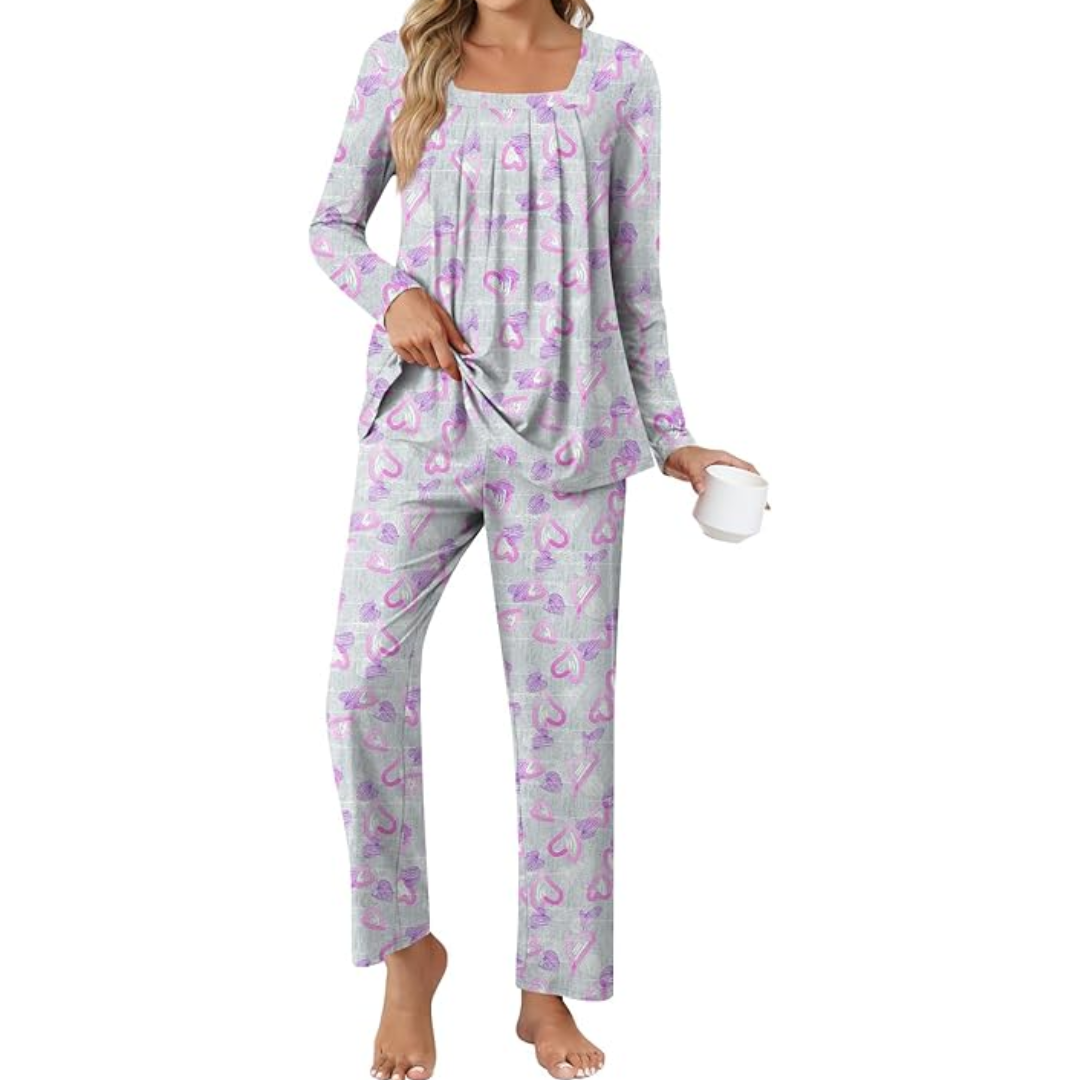 Frau in grauem Pyjama mit rosa Herzmuster, hält eine Tasse, gemütliche Nachtwäsche.