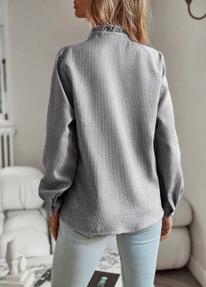 Frau in grauer Strickbluse und blauer Jeans, modisch, lässig, Innenraum.