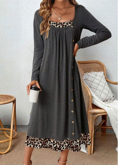Frau in grauem Maxikleid mit Leopardenmuster, hält Kaffeebecher, sitzt auf Rattanstuhl.