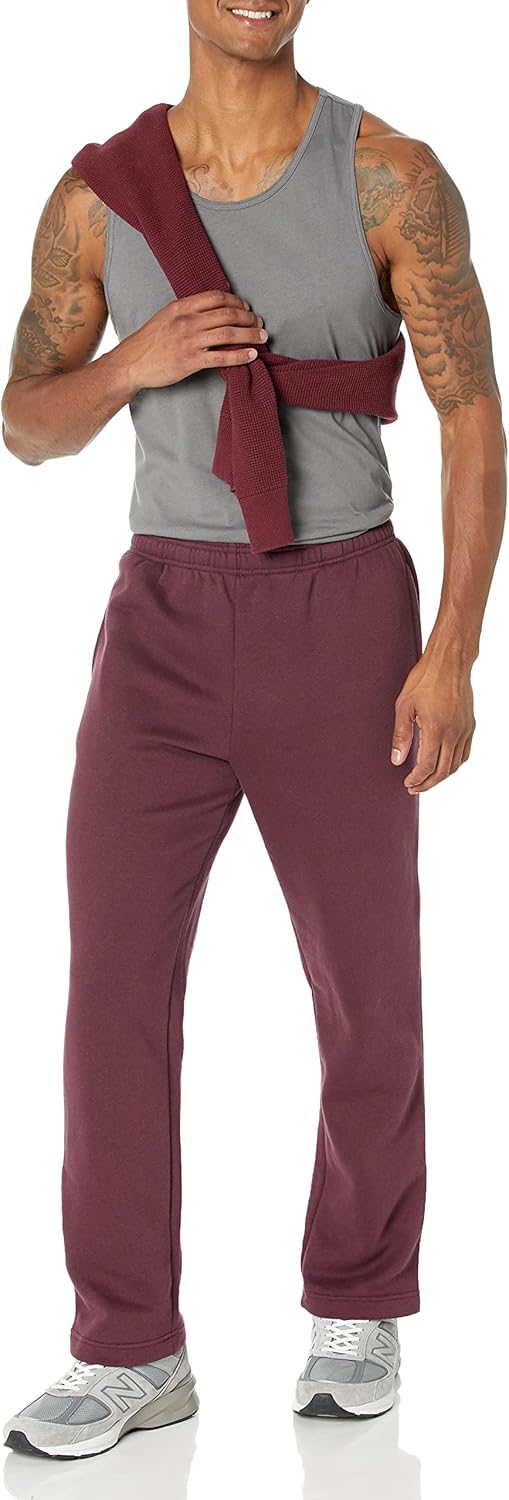 Mann in grauem Tanktop und bordeauxroter Jogginghose, lächelnd, sportlich, Freizeitkleidung.