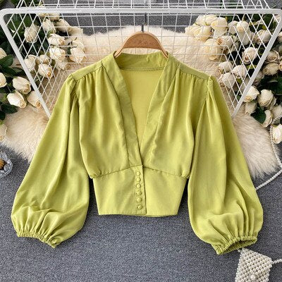 Grüne Damenbluse mit Puffärmeln, V-Ausschnitt, Knopfleiste, elegant, modisch, aus Baumwolle.