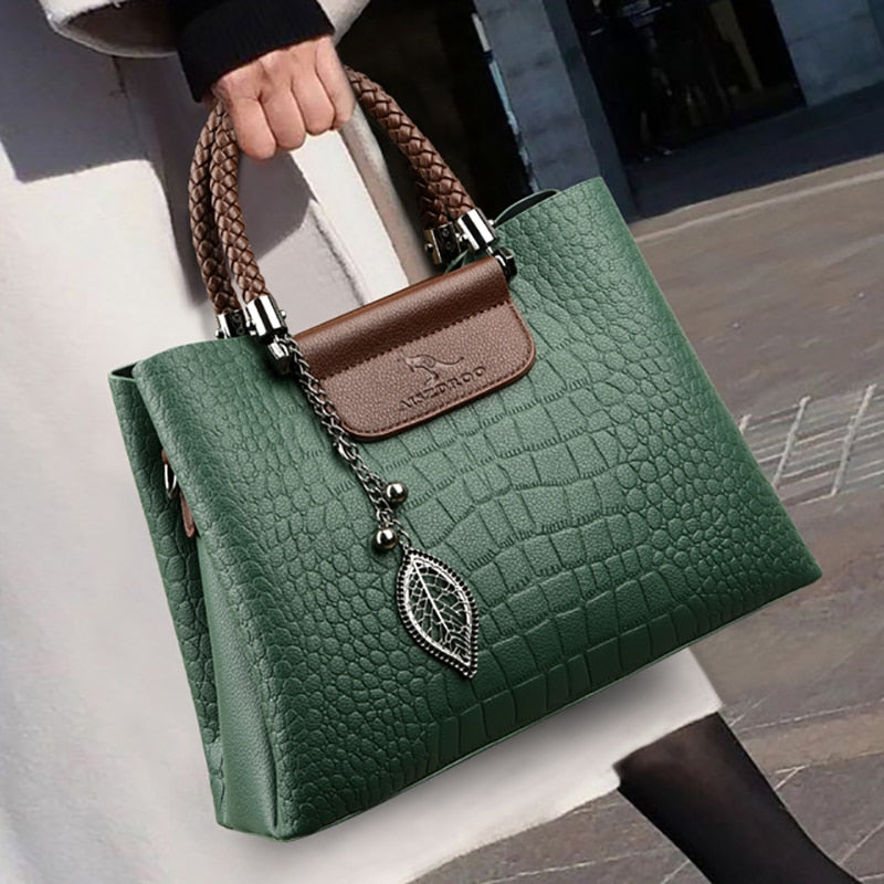 Grüne Damenhandtasche aus Leder mit Krokodilprägung und braunen Griffen, elegantes Design.