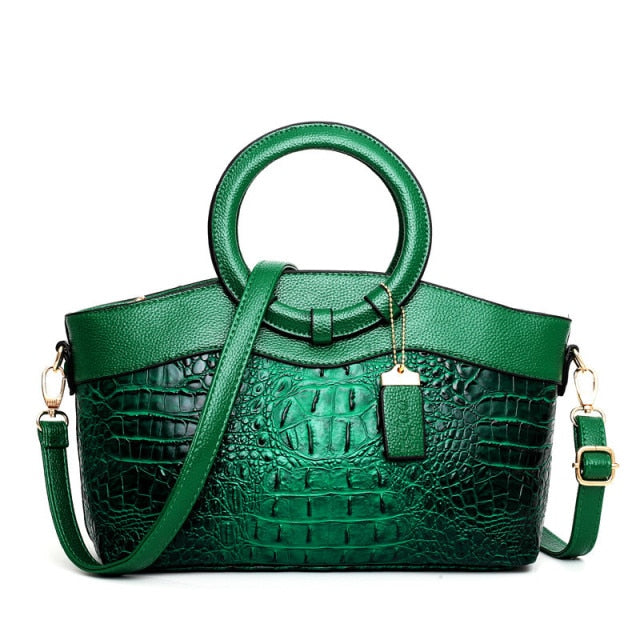 Grüne Krokodilleder-Handtasche mit rundem Griff und Schulterriemen, modisches Damenaccessoire.
