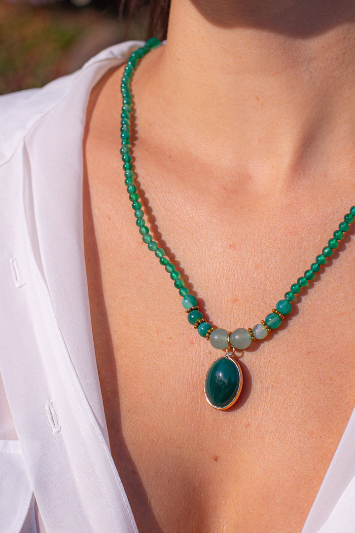 Frau mit grünem Edelstein-Halskette, weißes Hemd, eleganter Schmuck, modisches Accessoire.