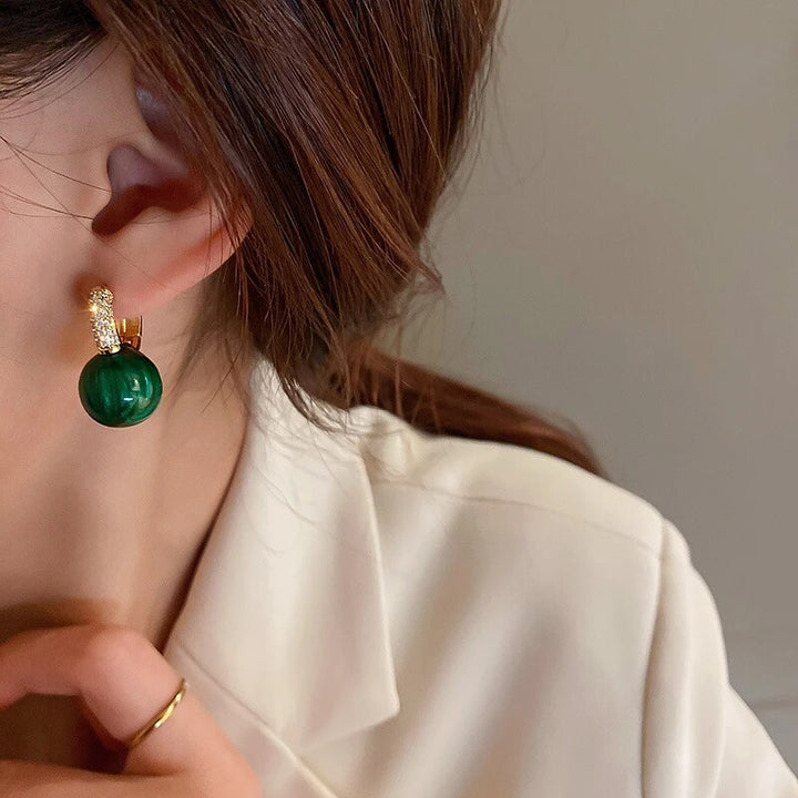 Frau mit grünen Perlenohrringen, luxuriöse Schmuckaccessoires, elegantes Design.