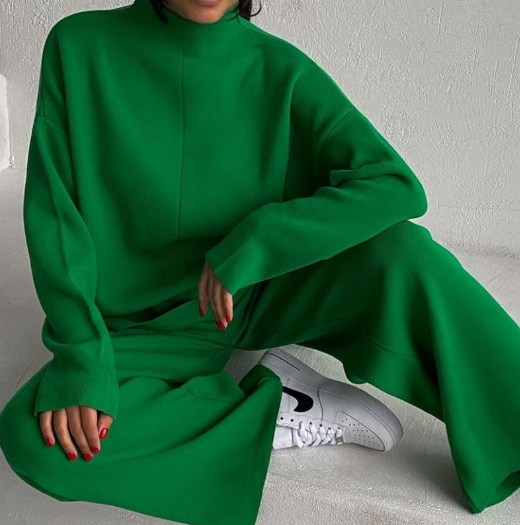 Frau in grünem Oversize-Pullover und Hose, weiße Sneakers, modisches Outfit, gemütlich.