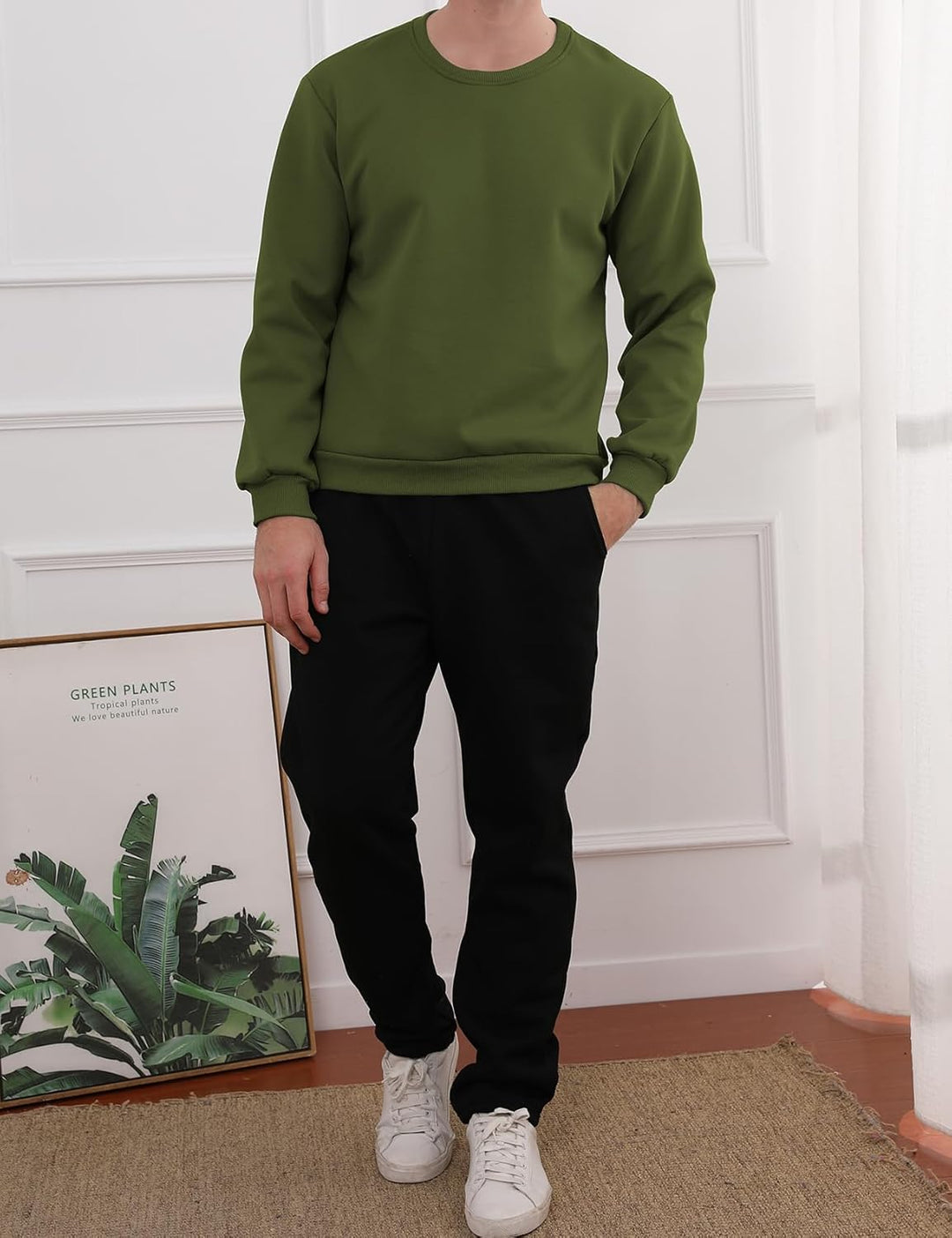 Mann in grünem Sweatshirt und schwarzer Hose, weiße Sneaker, moderne Freizeitmode.