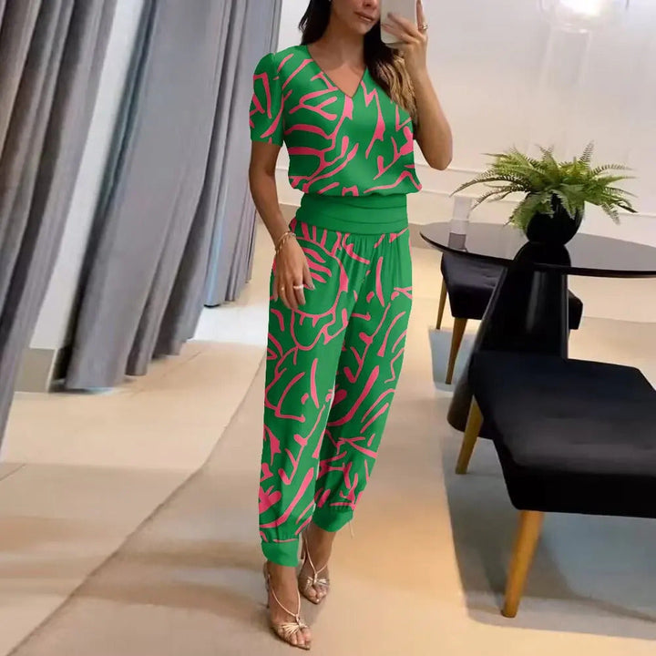 Frau in grünem, gemustertem Jumpsuit, Wohnzimmer, moderne Einrichtung, Pflanzen, Mode.