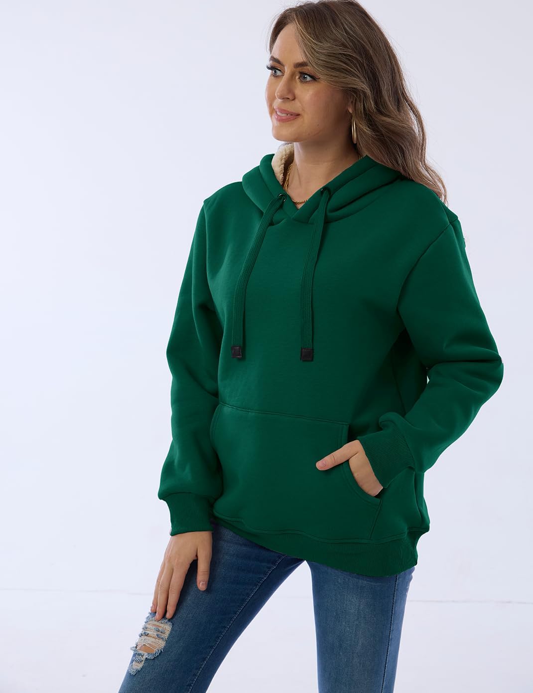 Frau in grünem Kapuzenpullover und blauer Jeans, lässige Mode, bequeme Freizeitkleidung.