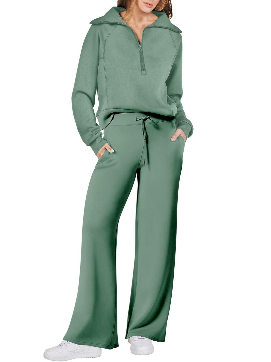Frau in grünem Freizeitanzug, Pullover mit Reißverschluss, weite Hose, weiße Sneaker.