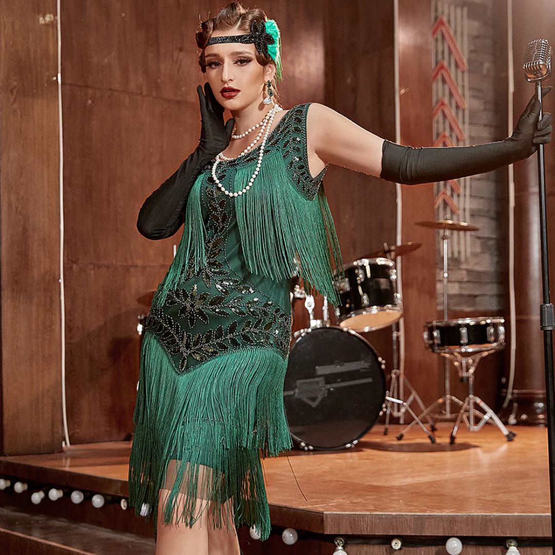 Frau im grünen Charleston-Kleid mit Fransen, Perlenkette, langen Handschuhen, Retro-Mikrofon.