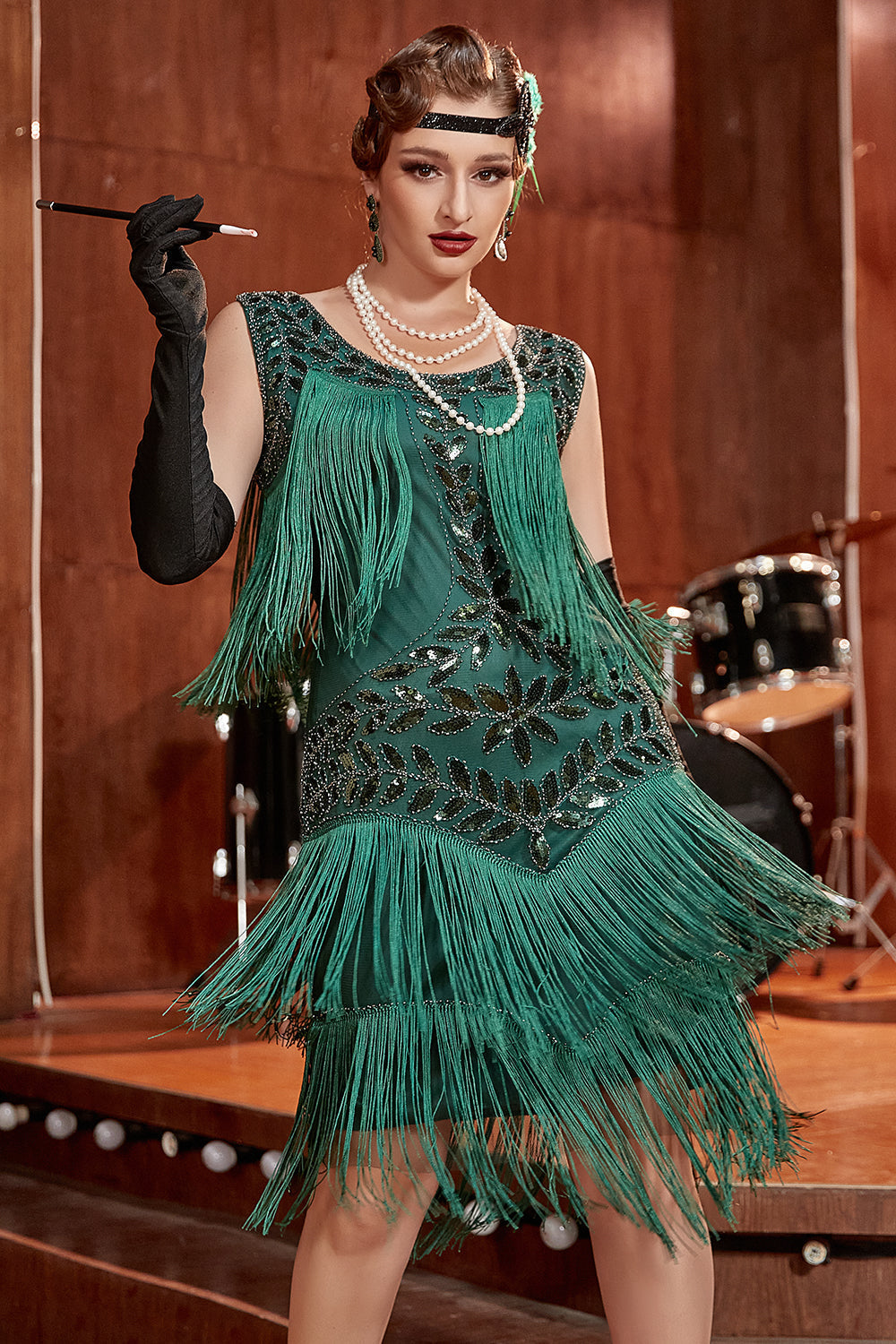 Frau im grünen Charleston-Kleid mit Fransen, Perlenkette, schwarzem Handschuh, Vintage-Stil.