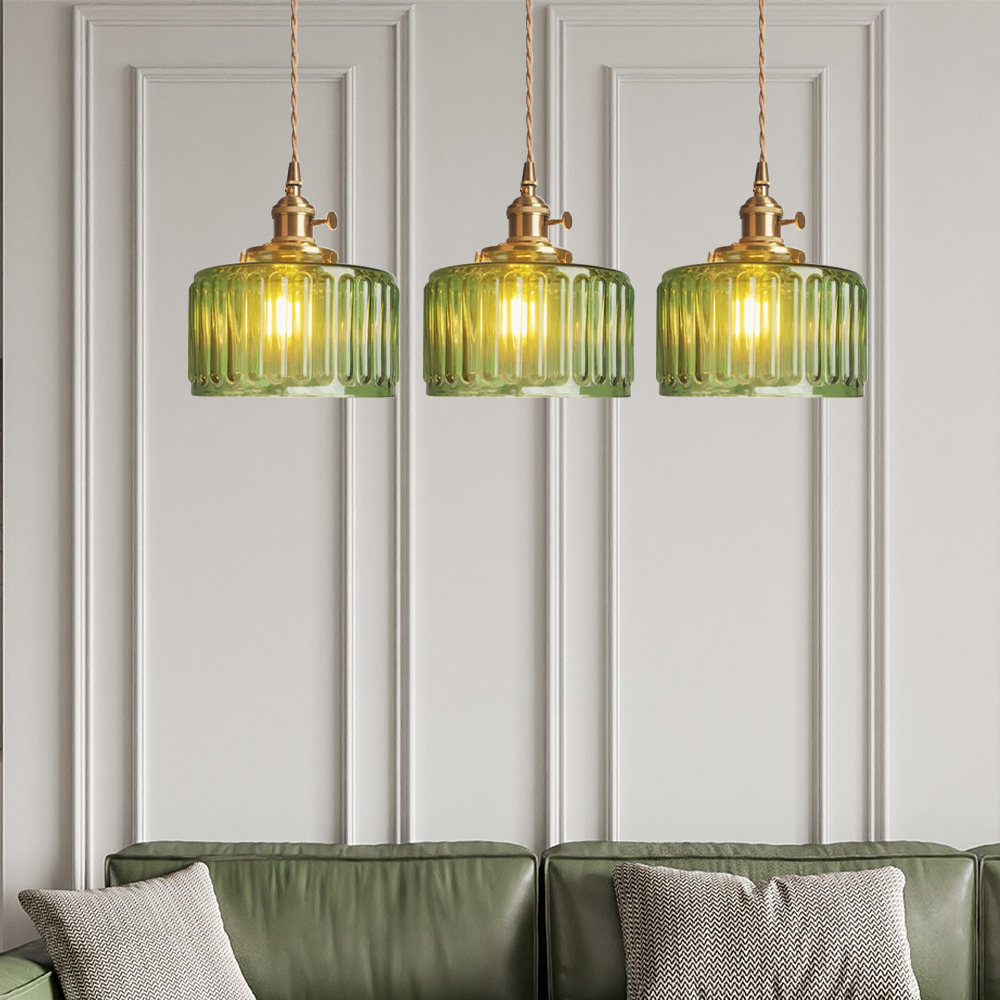 Drei grüne Glas-Pendelleuchten über grünem Sofa, moderne Wohnzimmerbeleuchtung.