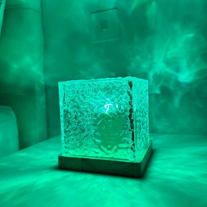 Grüne LED-Würfellampe aus Glas auf Holzbasis, stimmungsvolle Beleuchtung, modernes Design.