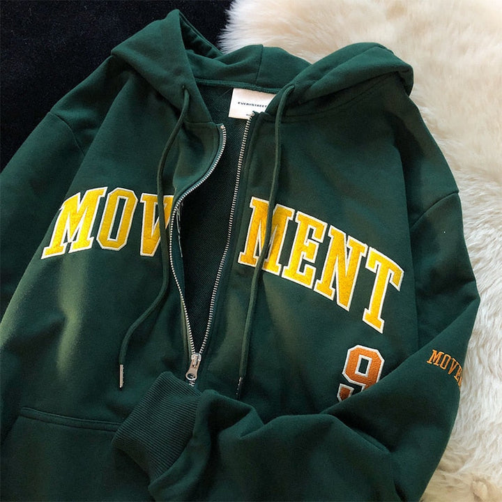 Dunkelgrüner Kapuzenpullover mit gelbem "MOVEMENT" Schriftzug, Reißverschluss, Baumwolle.