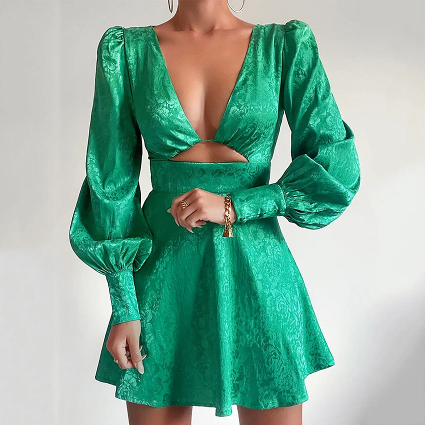 Frau in grünem Minikleid mit Puffärmeln und tiefem Ausschnitt, elegantes Abendoutfit.