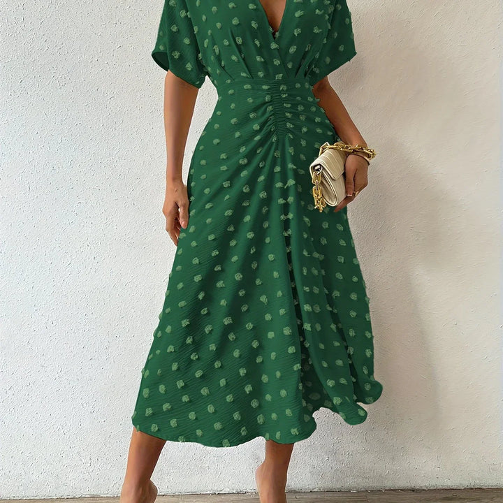 Grünes Damenkleid mit V-Ausschnitt, gepunktet, knielang, elegant, Sommermode.