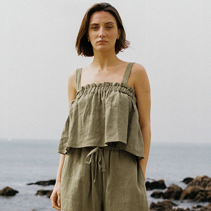 Frau in olivgrünem Leinen-Top und Hose am Strand, Sommermode, lässiger Stil.