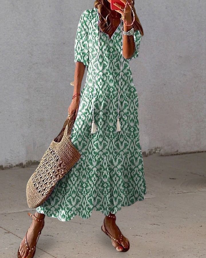 Frau in grünem Boho-Kleid mit Muster, Strohtasche, Sandalen, Sommermode.