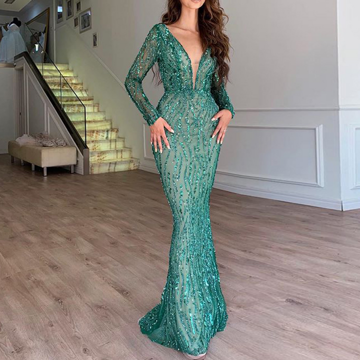 Frau in elegantem, grünem Abendkleid mit Pailletten, V-Ausschnitt, langärmelig, glamourös.