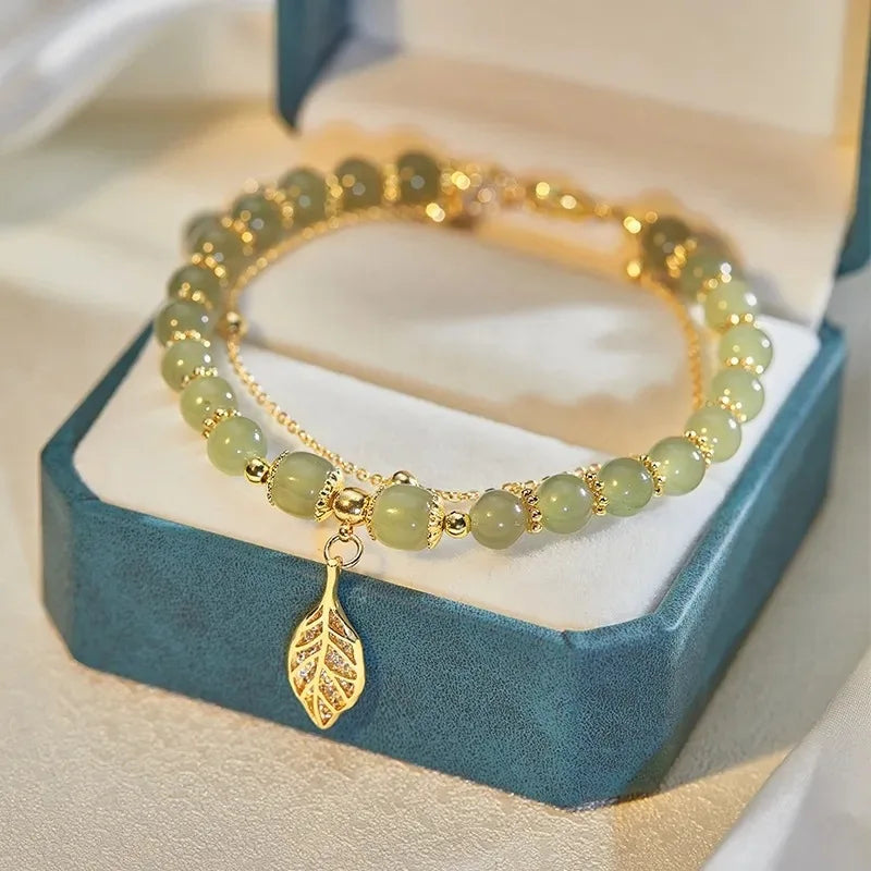 Grünes Jade-Armband mit goldenen Perlen und Blattanhänger in Schmuckschatulle.
