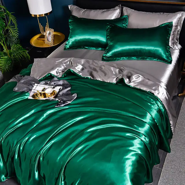 Grünes Seidensatin-Bettwäsche-Set mit Kissen auf grauem Bett, luxuriöses Schlafzimmer-Dekor.
