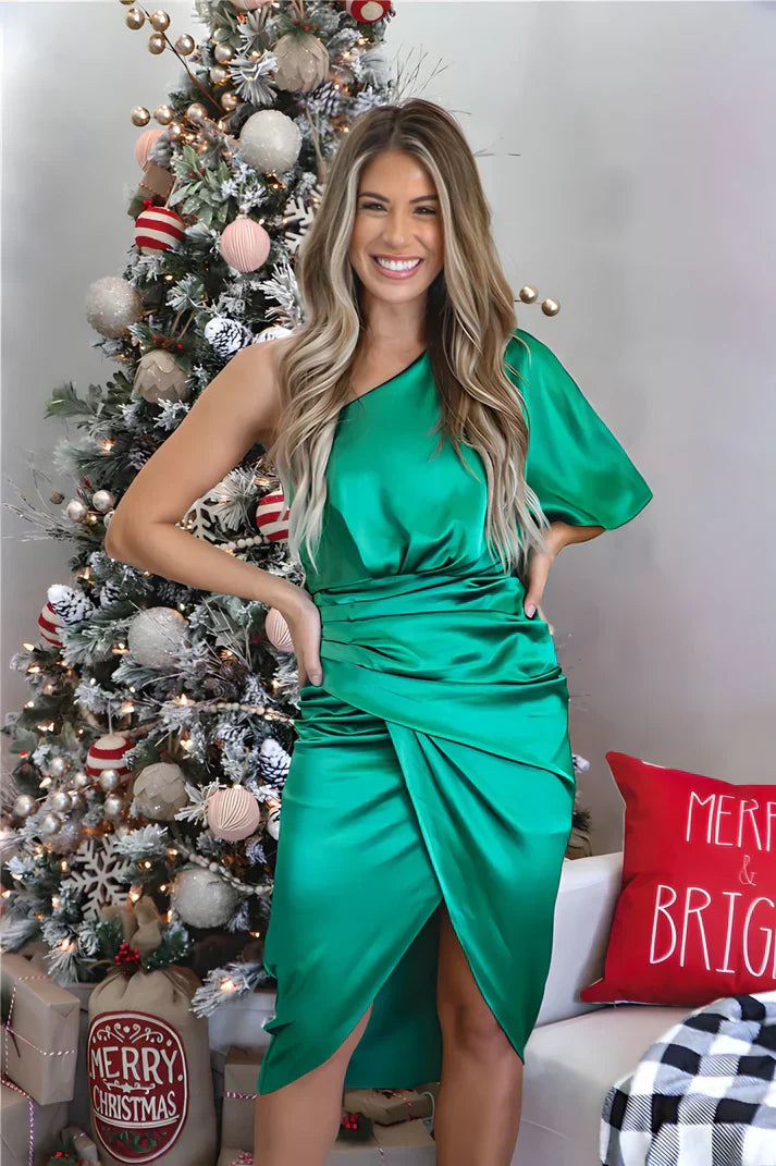 Frau in grünem Satinkleid vor Weihnachtsbaum, festliche Dekoration, Weihnachtsfeier Outfit.