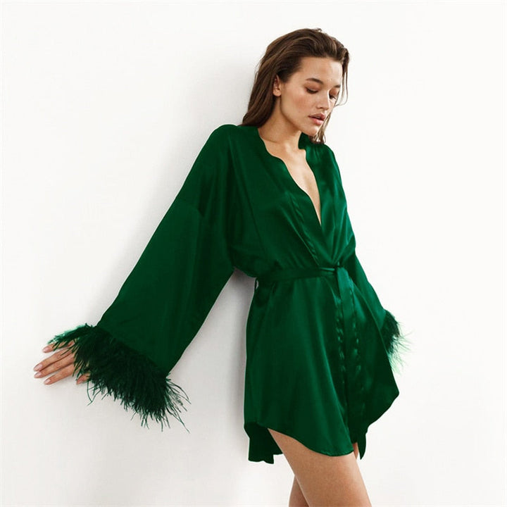 Frau in grünem Satin-Kimono mit Federn, elegantes Nachtwäsche-Outfit, Modefotografie.