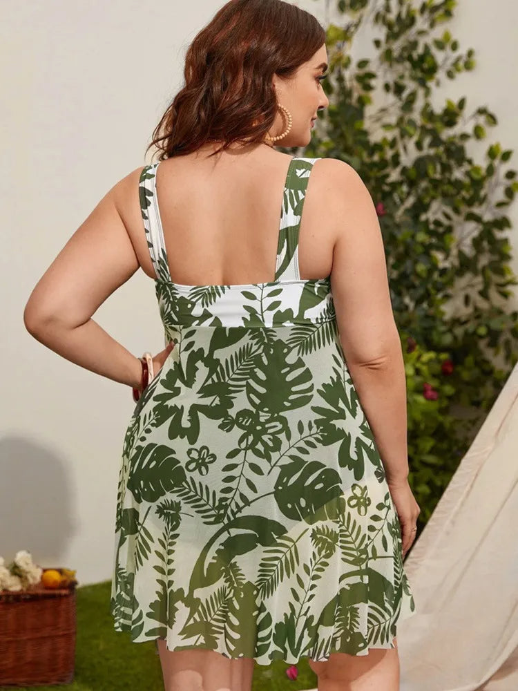 Frau im grünen, ärmellosen Sommerkleid mit tropischem Muster, Rückansicht, draußen.