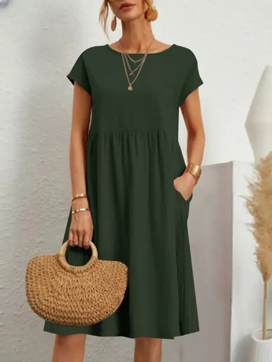 Frau in grünem Sommerkleid mit Strohtasche, goldenen Accessoires, modisch, elegant, Freizeitlook.