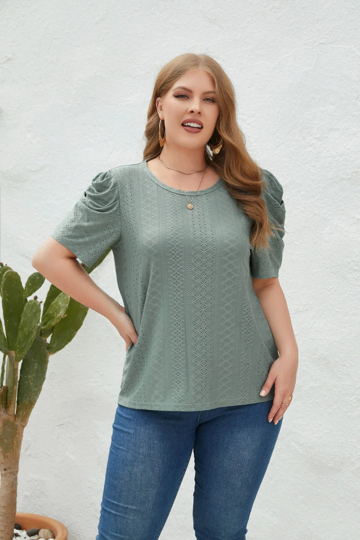 Frau in grünem Spitzen-T-Shirt und blauer Jeans vor weißer Wand, Mode, Freizeitkleidung.