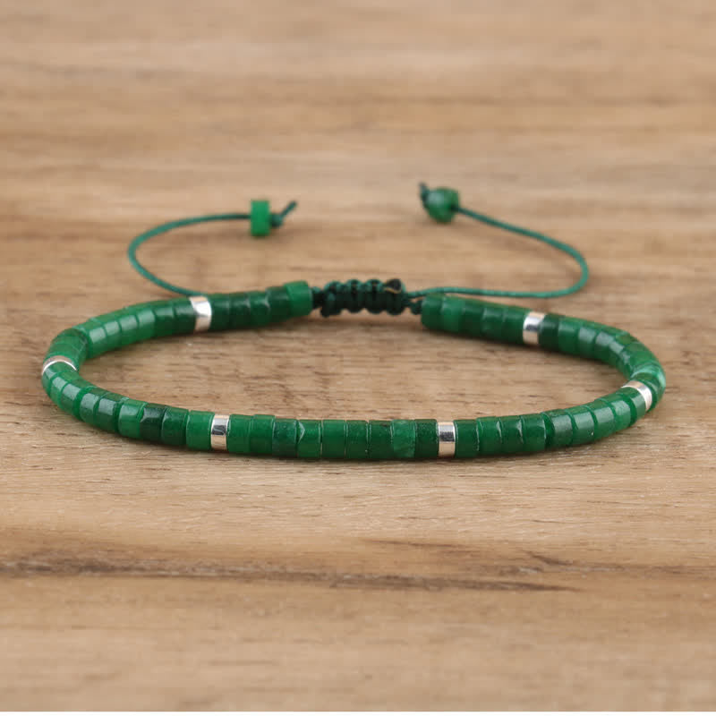 Grünes Perlenarmband aus Jade mit verstellbarem Verschluss auf Holzoberfläche.