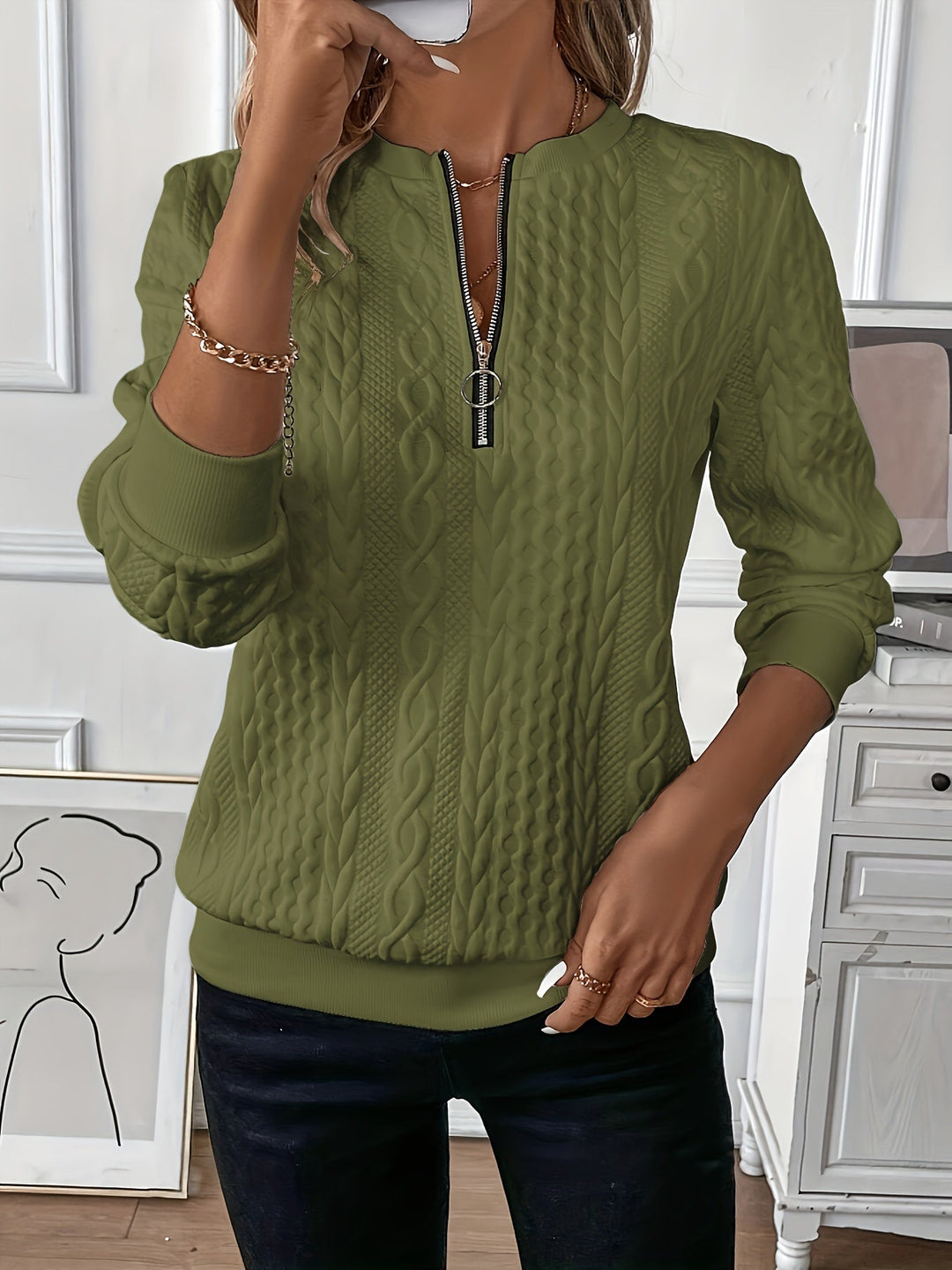 Frau trägt olivgrünen Strickpullover mit Reißverschluss, Zopfmuster, modisch, gemütlich.