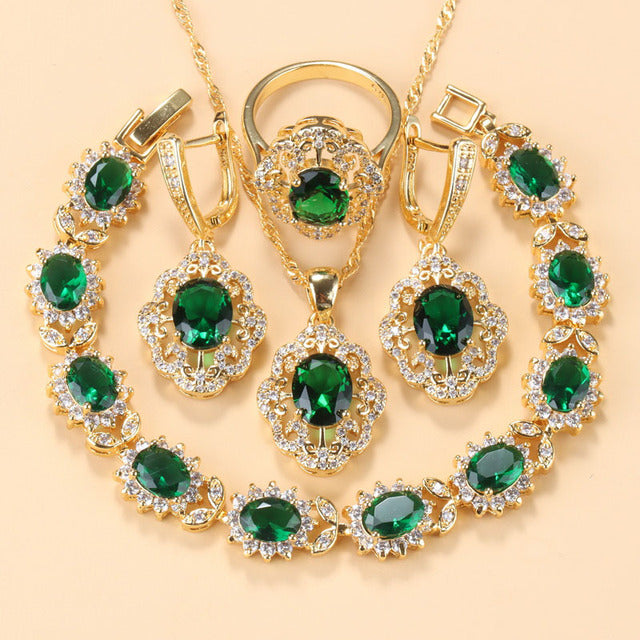 Goldene Schmuckset mit olivgrünen Zirkonia, bestehend aus Armband, Ring und Anhängern.