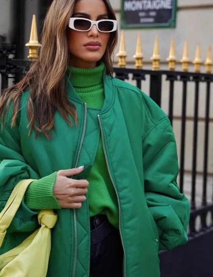 Frau in grüner Jacke und Pullover, weiße Sonnenbrille, modisch, urbaner Stil.