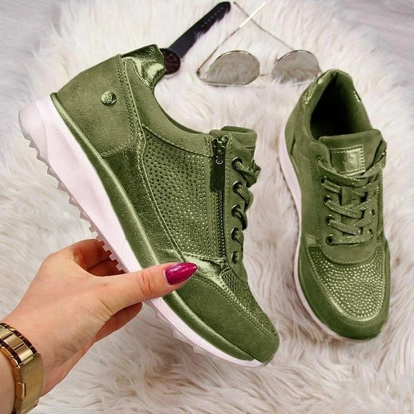 Grüne Damen-Sneaker aus Wildleder mit Reißverschluss und Schnürsenkeln auf weißem Teppich.