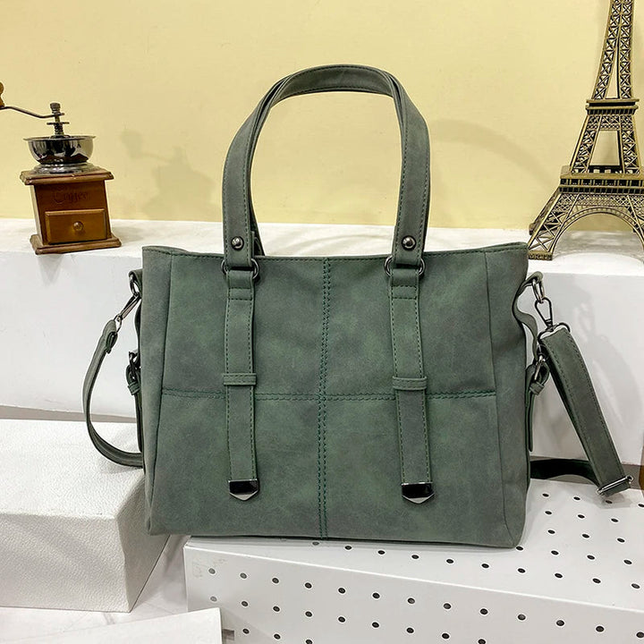 Grüne Damenhandtasche aus Leder mit Schulterriemen, elegant, modisch, vor Eiffelturm-Dekor.