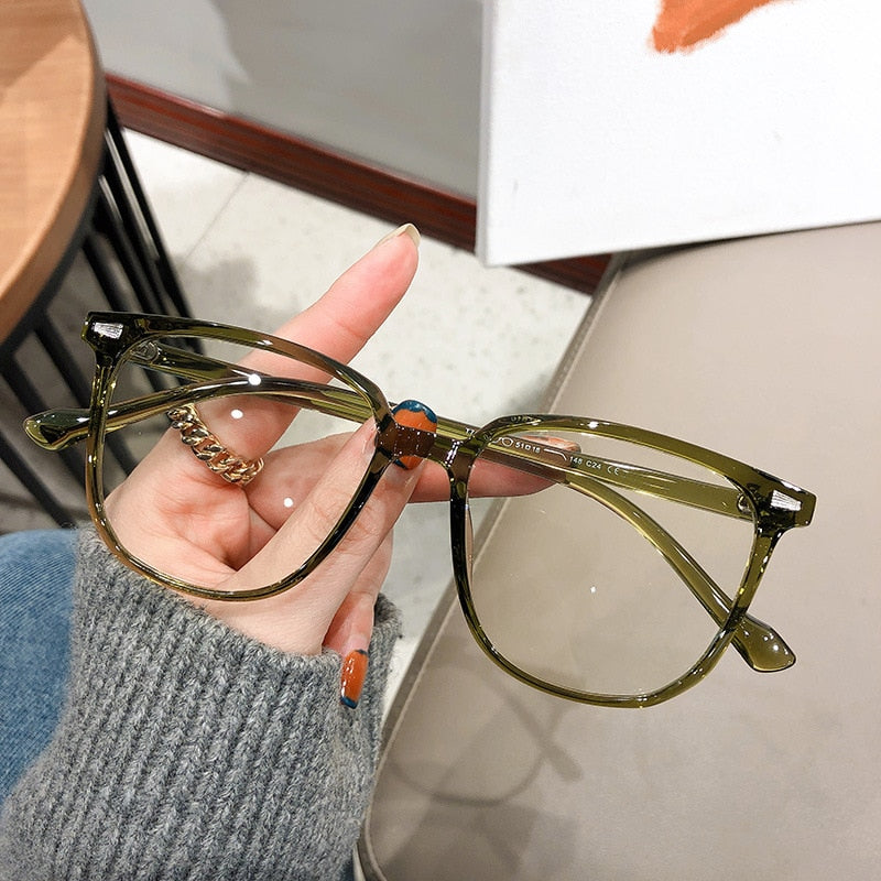 Grüne Brille mit transparentem Rahmen, modisches Accessoire, Damenhand hält Brille.