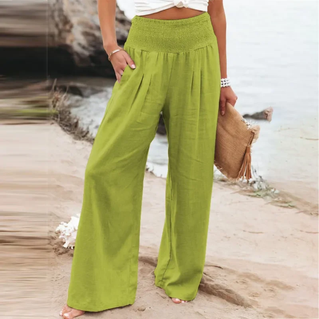 Frau in grüner Leinenhose am Strand, Sommermode, weite Passform, lässiger Stil.