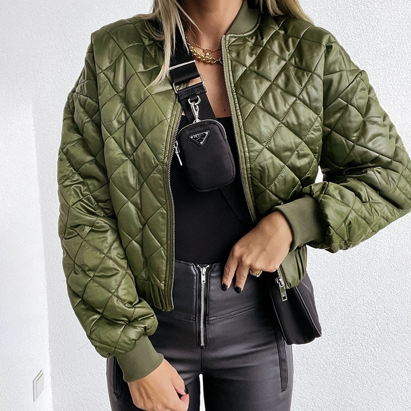 Frau trägt olivgrüne Steppjacke, schwarze Lederhose, schwarze Tasche, modisch, urban.