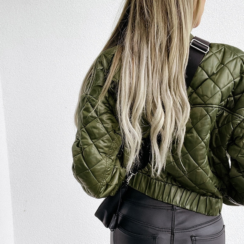 Frau mit olivgrüner Steppjacke und langen blonden Haaren, modisch, Rückansicht.