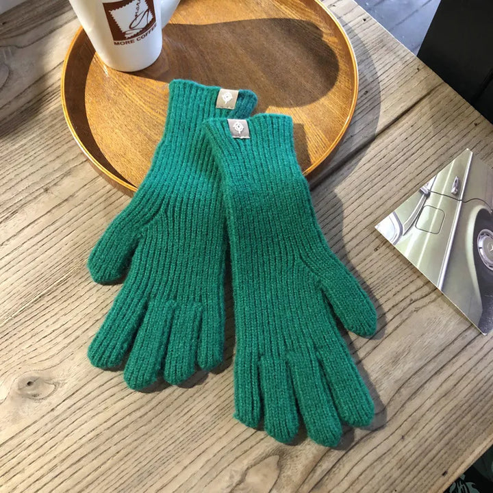Grüne Strickhandschuhe aus Wolle auf Holztisch, ideal für Wintermode und kaltes Wetter.